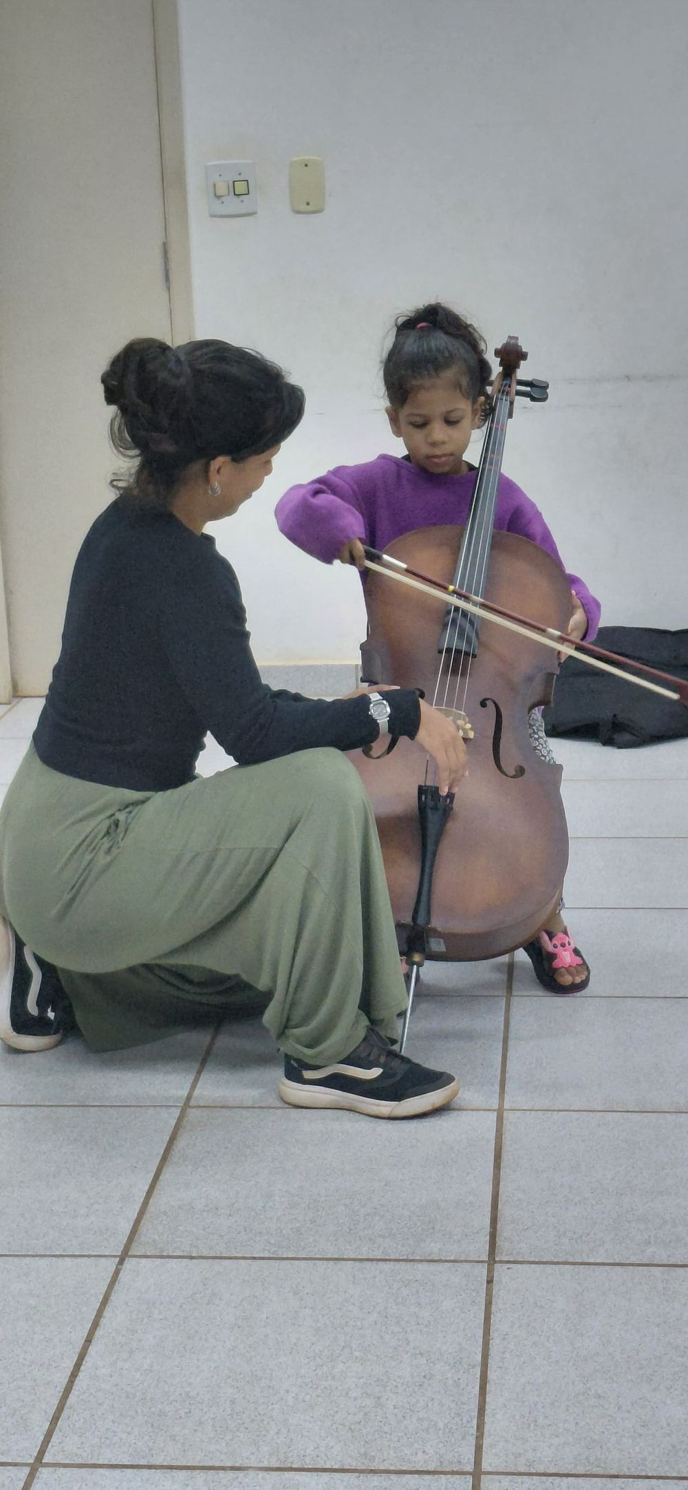 Professora ensinando violoncelo a uma criança pequena